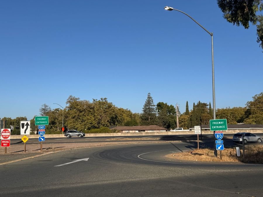 Entrance ramp to Interstate 80 East in Vallejo, California, with freeway entrance signs and cars driving toward the highway under a clear blue sky.