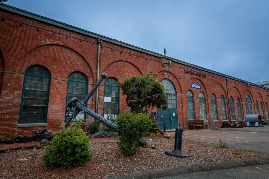 Historic red-brick building of the Mare Island Museum in Vallejo, featuring large arched windows and a navy anchor sculpture out front.