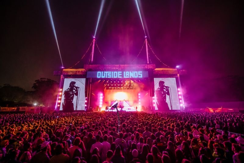 Crowd enjoying a nighttime concert with bright lights at the Outside Lands music festival in San Francisco.