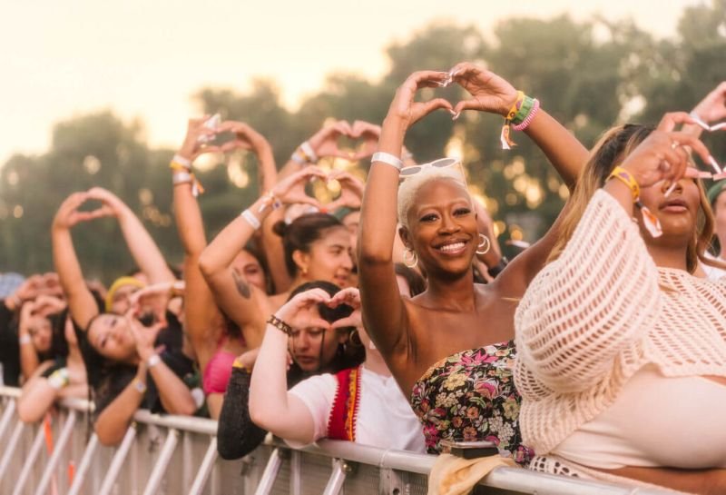 Smiling festival goers making heart signs with their hands at the Sol Blume music festival in Sacramento.