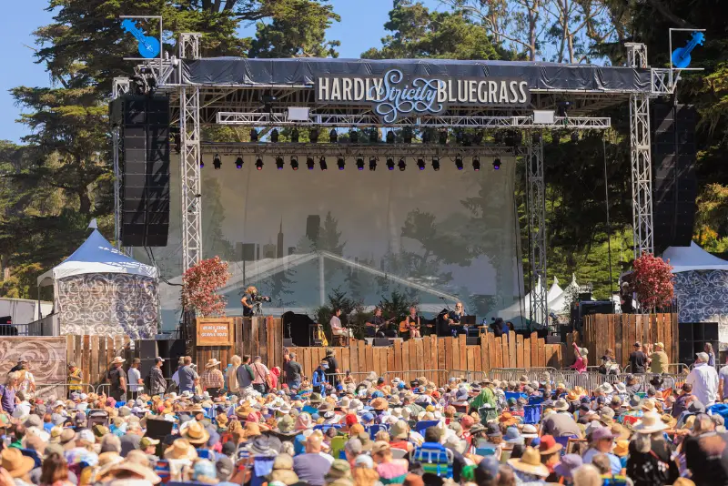 Audience gathered on blankets and chairs watching a daytime performance at the Hardly Strictly Bluegrass festival in Golden Gate Park, San Francisco.